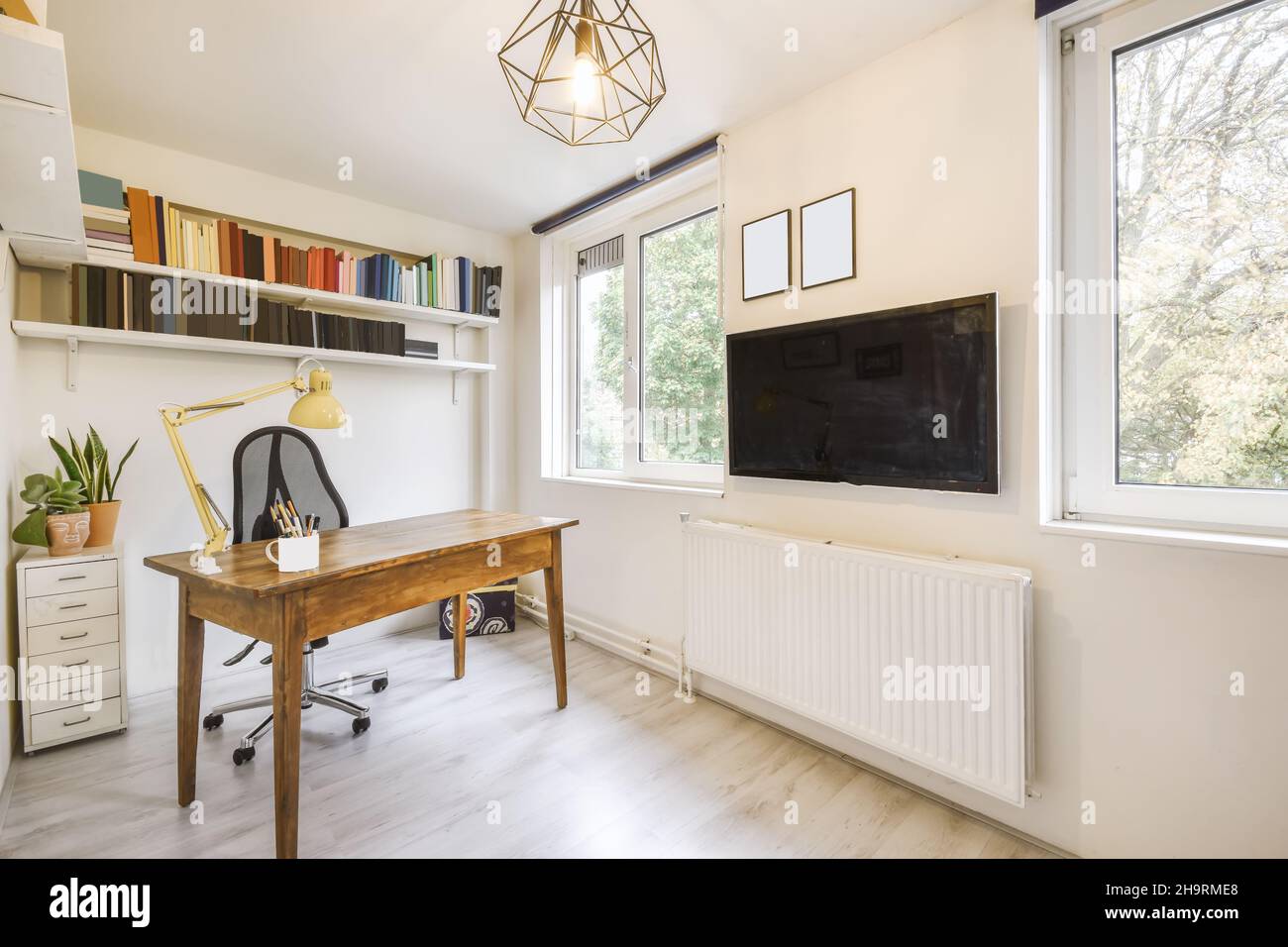 Accogliente area studio con tavolo in legno e comoda sedia nera Foto Stock