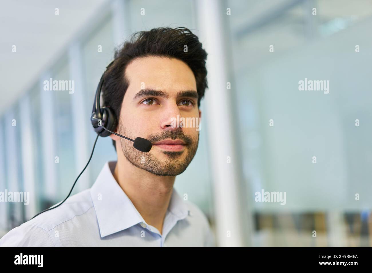 Giovane uomo d'affari con cuffie come operatore nella hotline di servizio nel call center Foto Stock