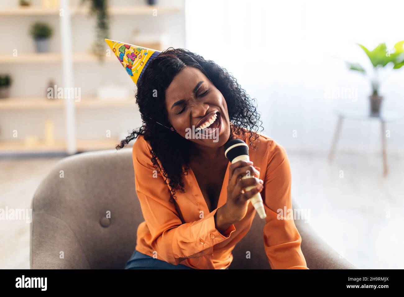 African American Woman Singing avendo Karaoke Birthday Party in Home Foto Stock