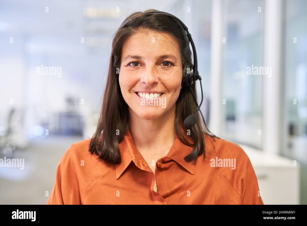Felice donna d'affari con la cuffia come consulente del cliente sulla hotline nel call center Foto Stock