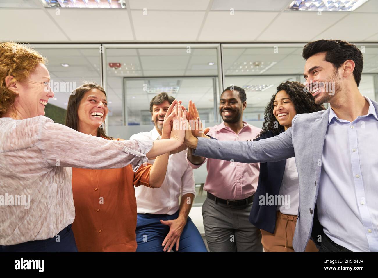 Il team internazionale di startup aziendale celebra il successo e lo spirito di squadra con cinque persone Foto Stock