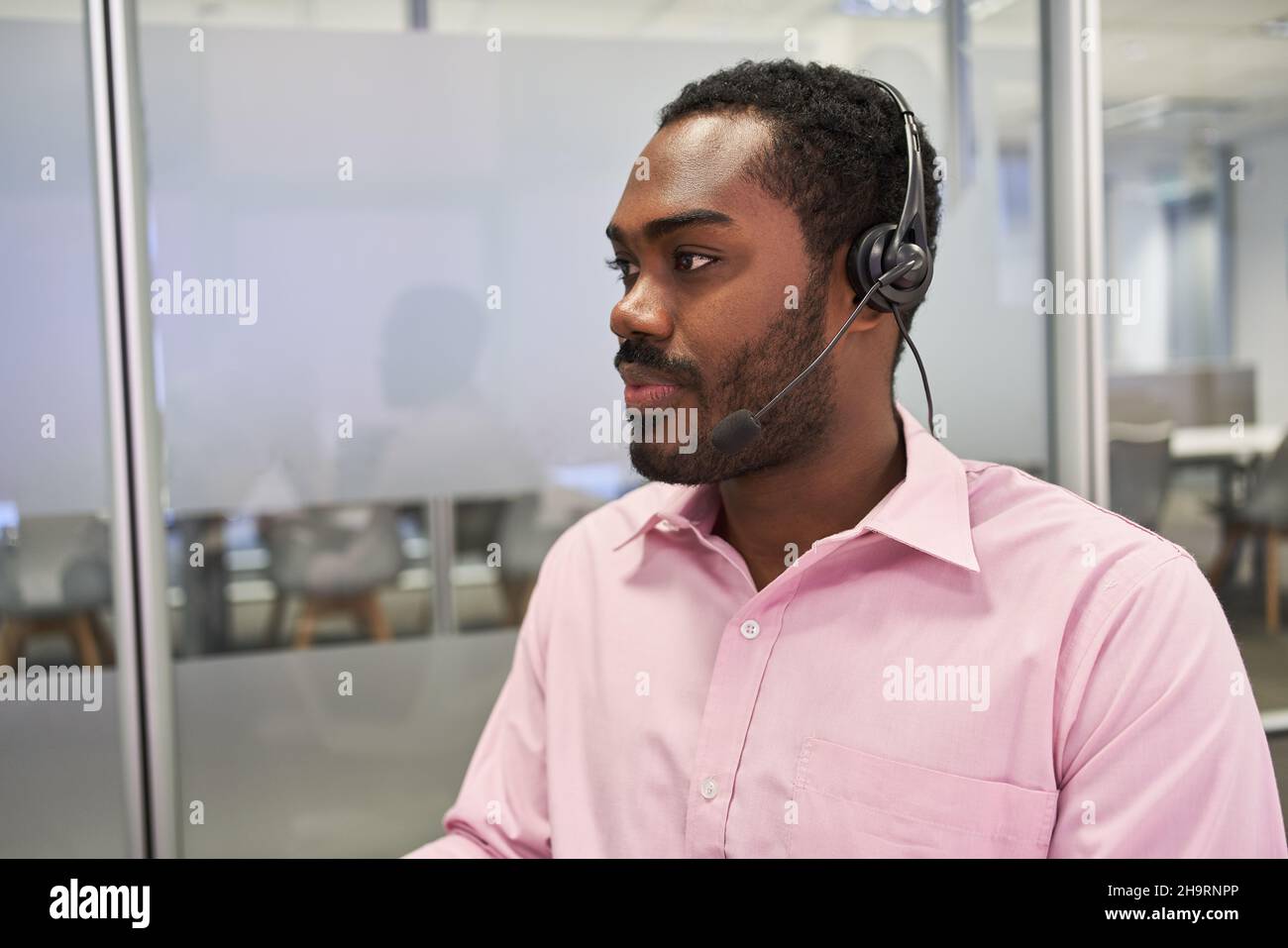 Uomo d'affari africano come consulente del cliente con cuffie sulla hotline nel call center Foto Stock