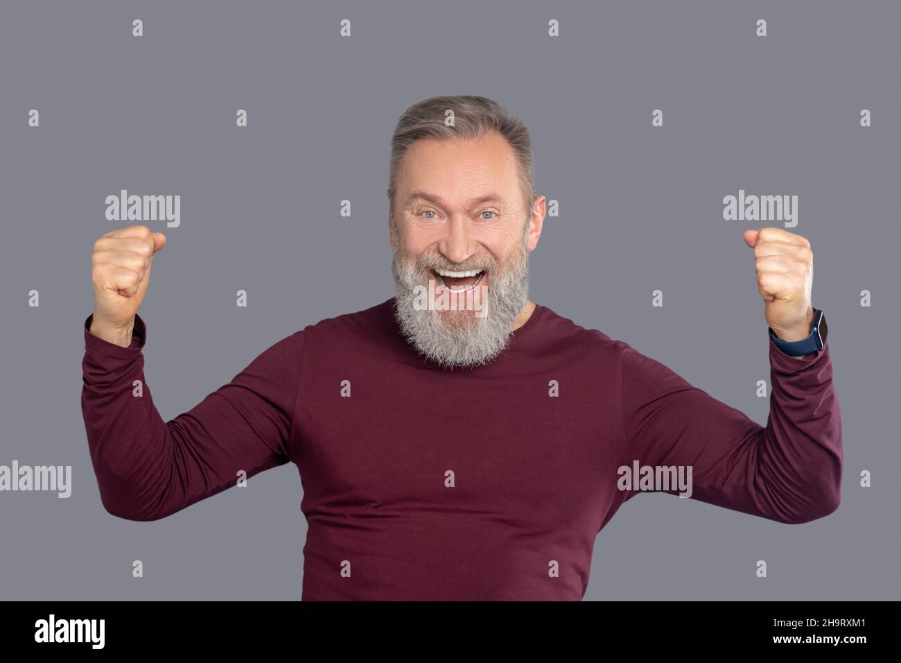 Uomo maturo in camicia borgogna che guarda positivo Foto Stock