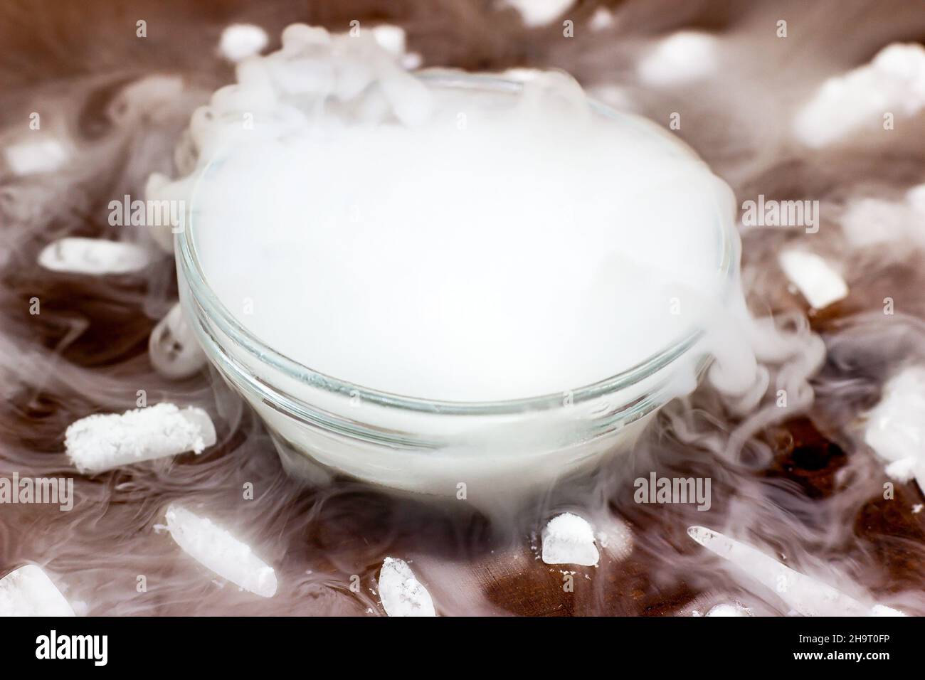 Ghiaccio secco fresco bianco (anidride carbonica congelata) con effetto fumo  nella ciotola di vetro sullo sfondo di legno marrone scuro Foto stock -  Alamy