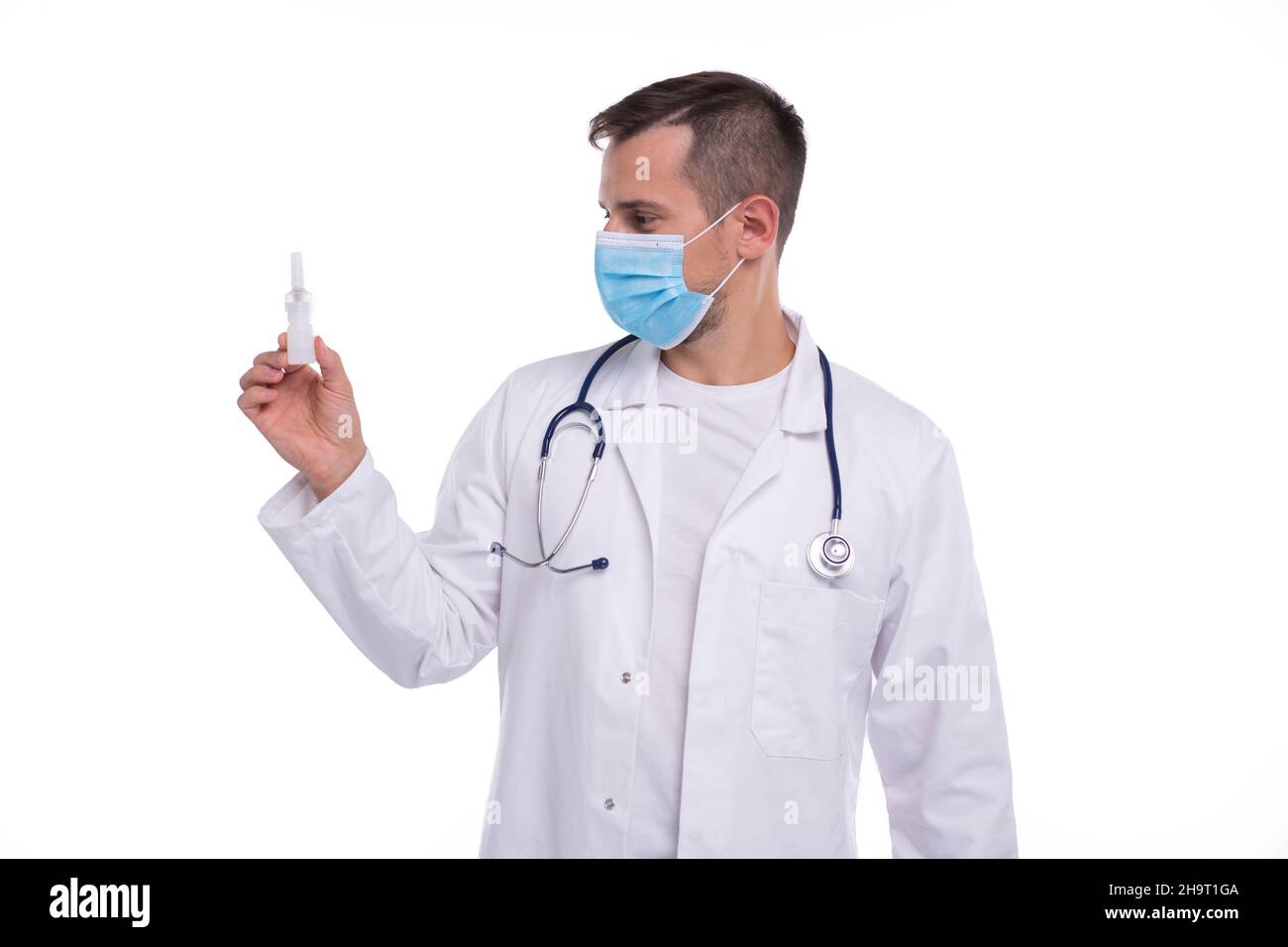 Spray nasale di tenuta medico isolato. Uomo medico con spray nasale in mani indossare maschera medica Foto Stock