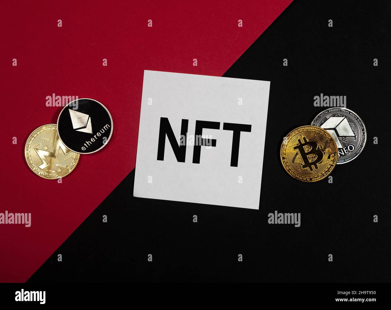 Acronimo NFT su carta nota su sfondo rosso e nero con monete di criptovaluta. Foto Stock