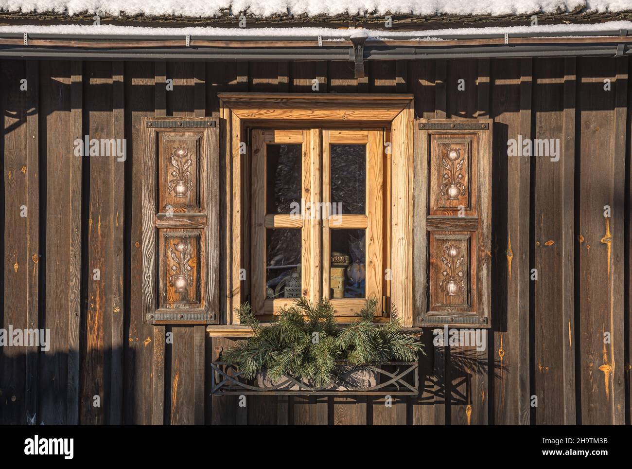 Vecchia finestra in legno con tetto coperto di neve con rami di abete e decorazioni Foto Stock