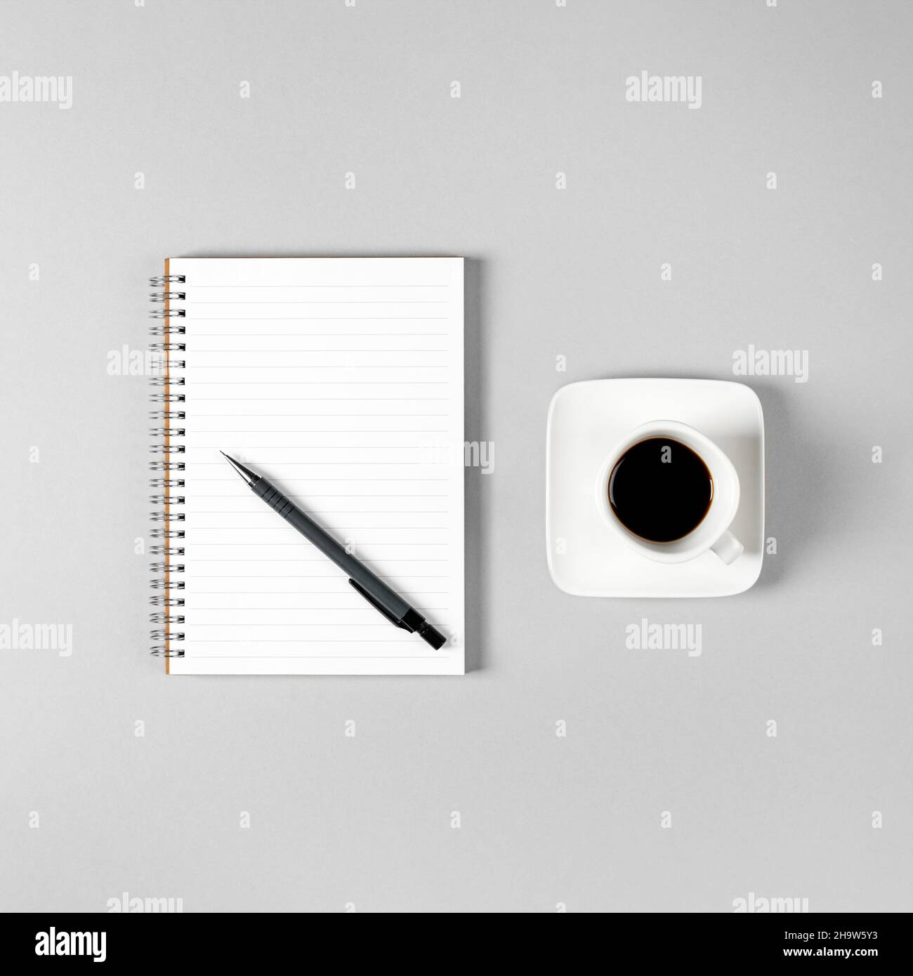 Blocco note, penna e una tazza di caffè isolato su sfondo grigio chiaro. Blocco note con spazio di copia. Ufficio, lavoro, stile discreto Foto Stock