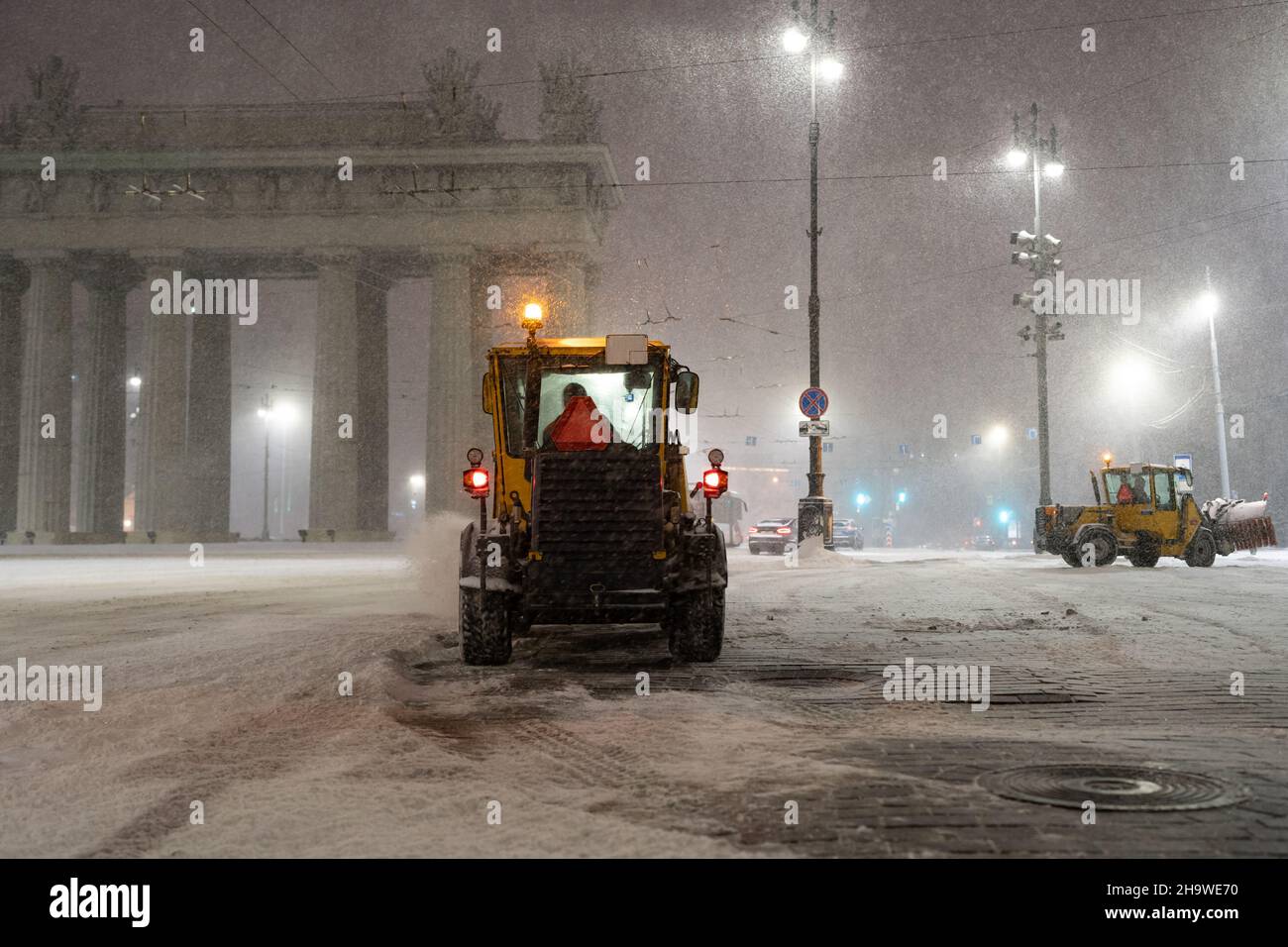 I veicoli spazzaneve funzionano in città dopo la nevicata. Trattori, bulldozer e spazzaneve puliscono la strada Foto Stock