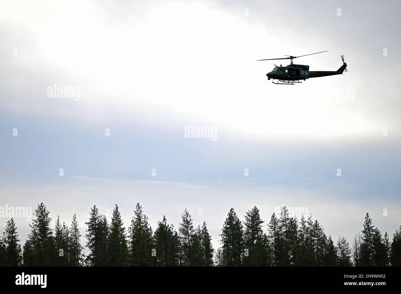 Un elicottero UH-1 Huey del 36th Rescue Squadron vola su una foresta mentre conduce addestramento di helocast con operatori di tattica speciali assegnati al 22nd Special Tactics Squadron alla base congiunta Lewis-McChord 2 dicembre 2021, alla base aerea di Fairchild, Washington. Il 22nd STS addestrato su indagine di campo aereo, salvataggio, e le tecniche mediche di emergenza durante un aiuto umanitario e un'esercitazione di soccorso in caso di calamità progettate per mantenere la prontezza per una risposta alle crisi a livello mondiale. Special Tactics è l’aria tattica del comando delle operazioni speciali degli Stati Uniti verso la forza di integrazione a terra, e le operazioni speciali dell’Air Force sono a galla Foto Stock