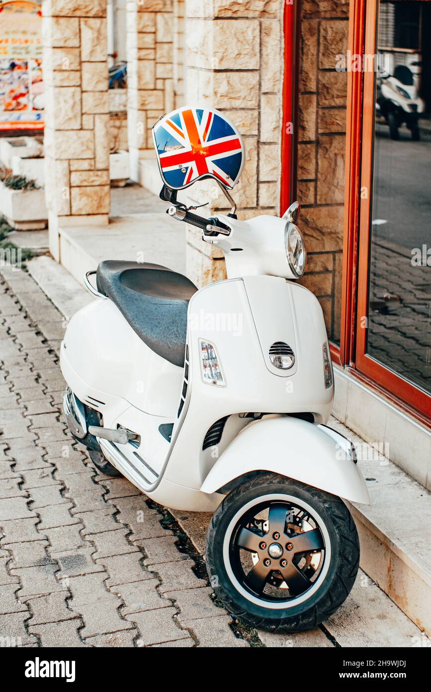 Uno scooter bianco con casco Union Jack si trova vicino a un edificio in pietra su un marciapiede Foto Stock