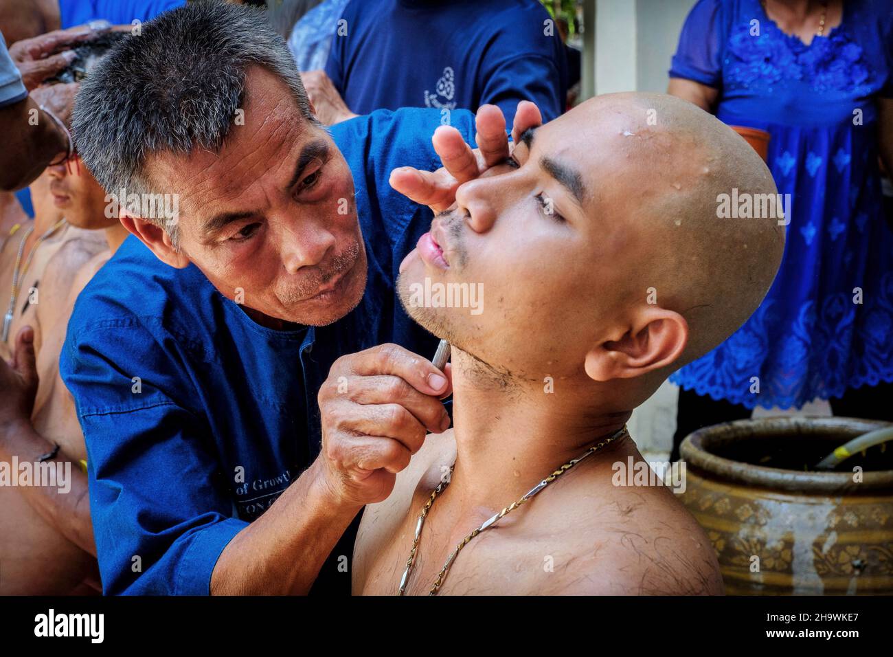 Un uomo ha la testa rasata prima di diventare un monaco buddista a Nakhon Nayok, Thailandia. Foto Stock