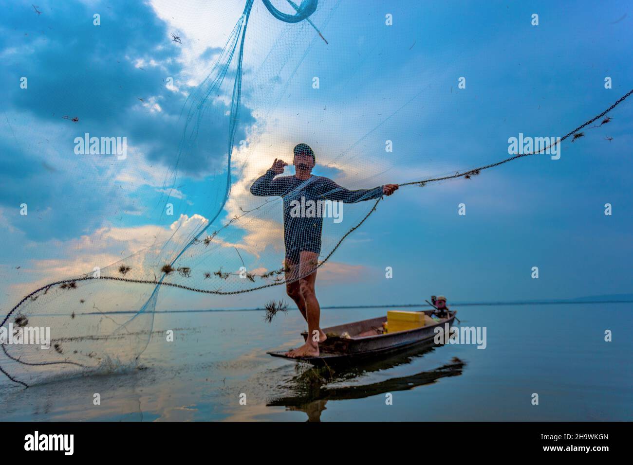 Pescatore gettando rete nel fiume Foto Stock