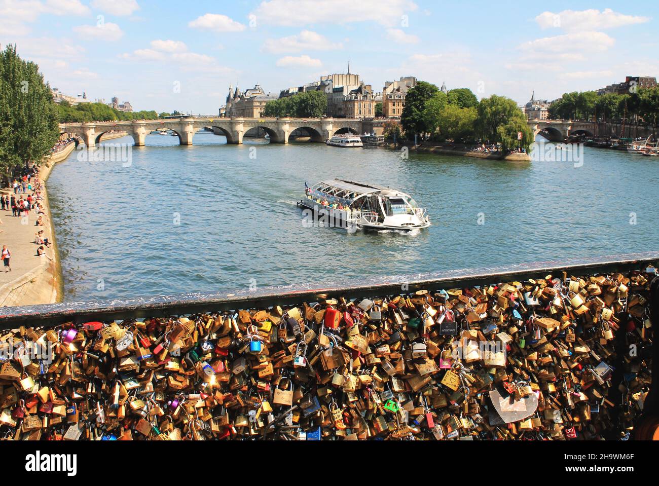 Vista dal ponte Pont des Arts sul fiume Senna, Parigi, Francia, con un tour in barca sull'acqua e "Love Locks" sulla ringhiera in primo piano. Foto Stock