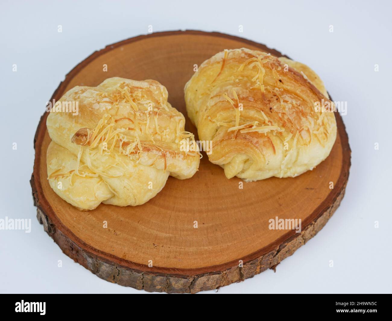primo piano di due croissant al formaggio su un tagliere di legno isolato su sfondo bianco Foto Stock
