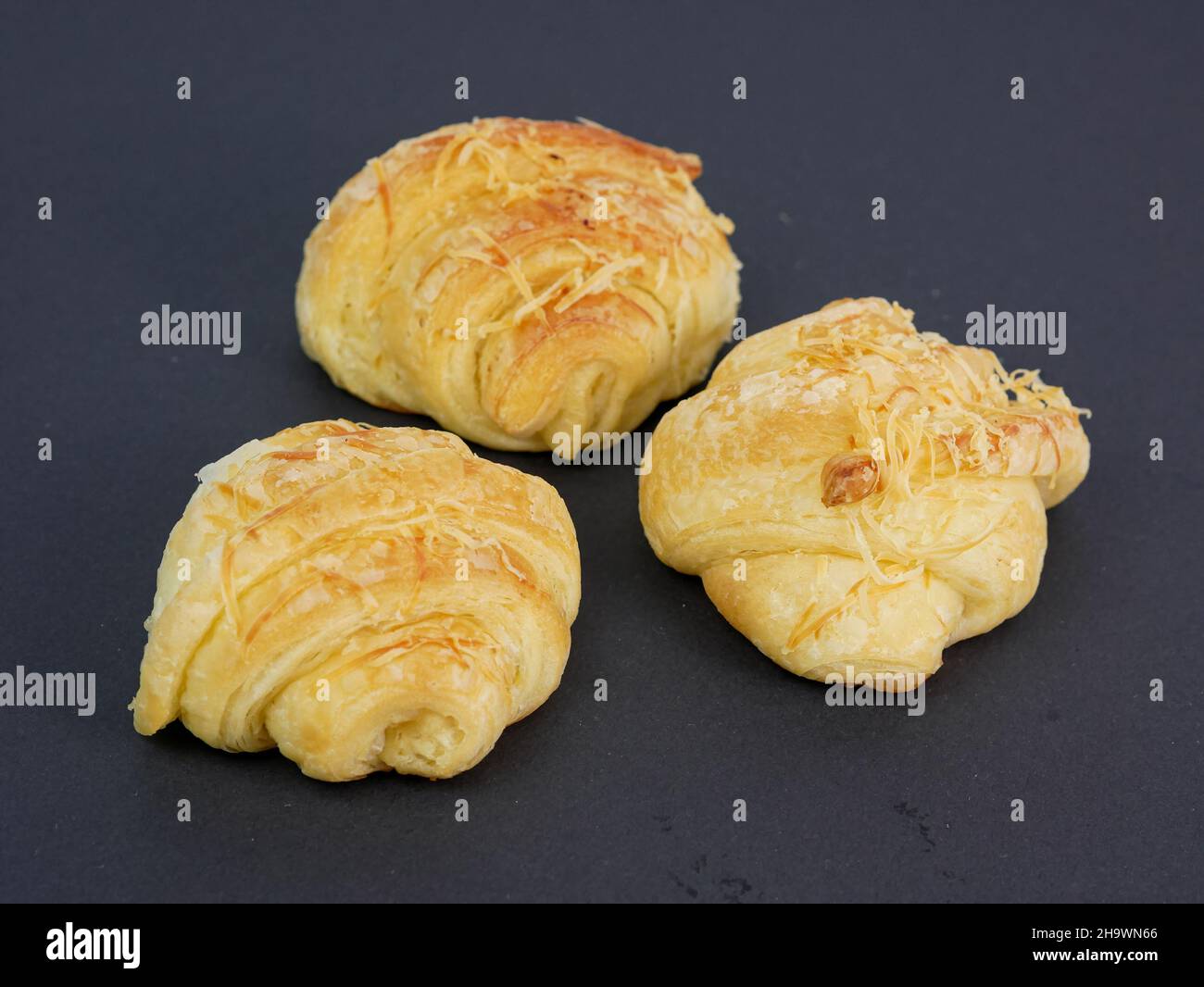 primo piano di tre croissant al formaggio su sfondo nero Foto Stock