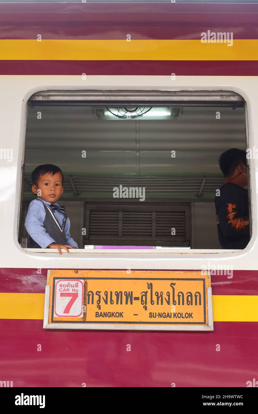 Ragazzo guardando fuori dal treno alla stazione ferroviaria, Bangkok, Thailandia Foto Stock