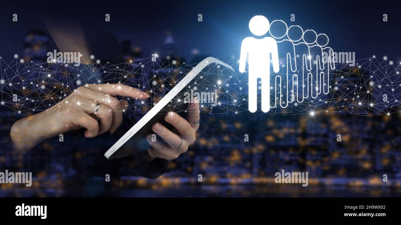 Risorse umane e concetto di team management. Mano touch tablet bianco con ologramma digitale umano, leader segno sulla città scuro sfondo sfocato. Autobus Foto Stock