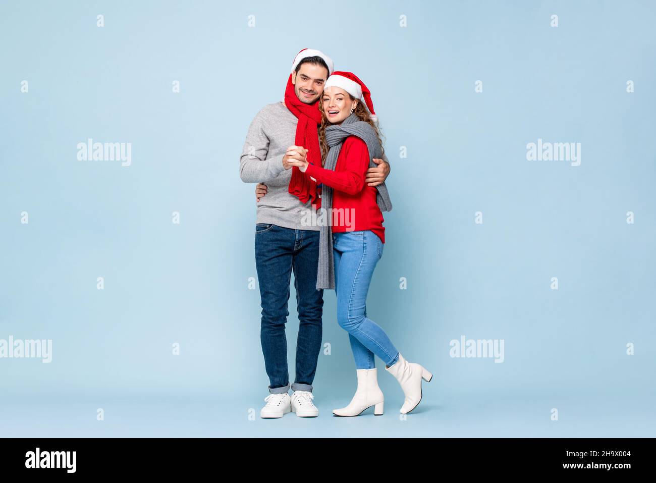 Ritratto a tutta lunghezza di felice coppia caucasica in abiti di Natale che si tengono in luce blu isolato sfondo studio Foto Stock