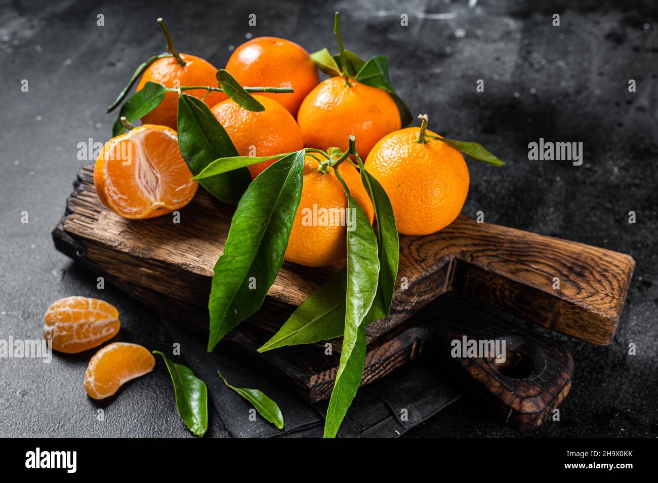 Mandarino arance o mandarino frutta con foglie su tavola di legno. Sfondo nero. Vista dall'alto Foto Stock