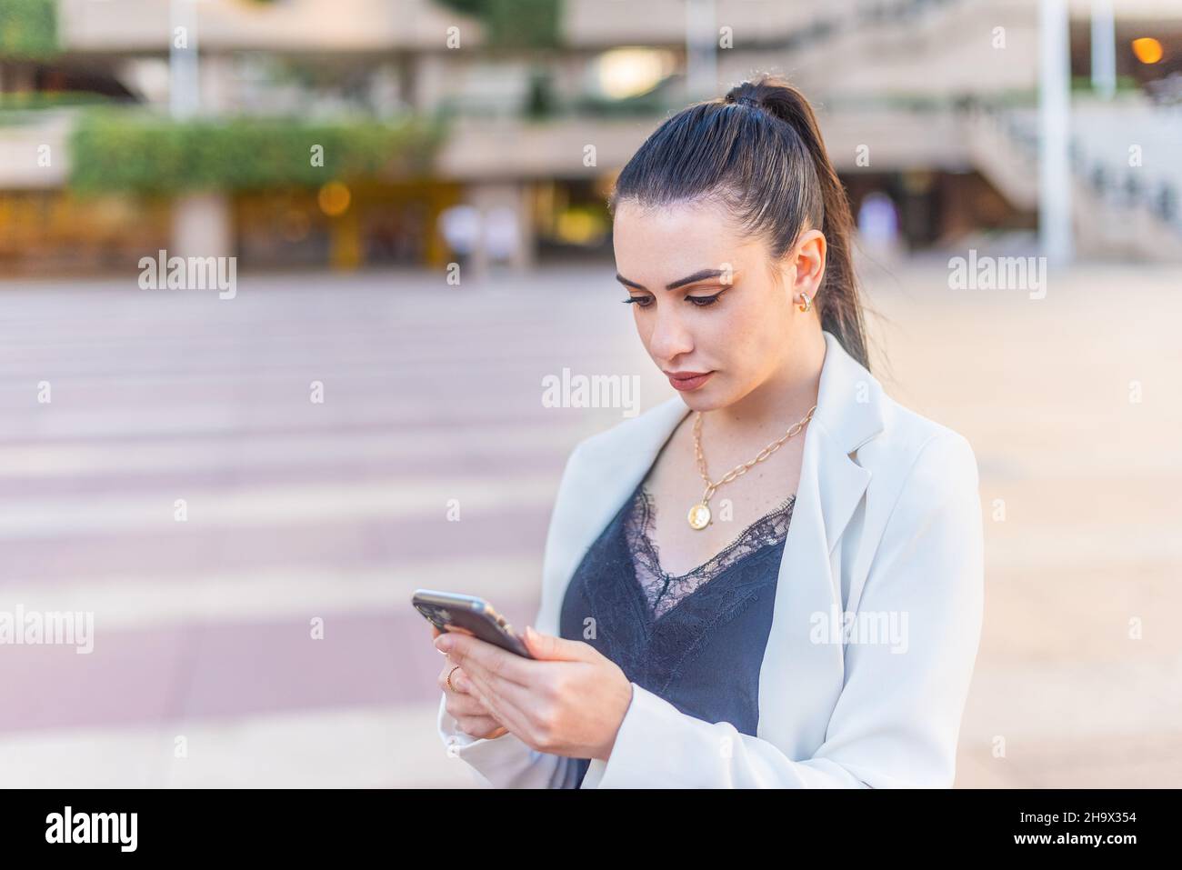donna elegante che digita sul suo cellulare Foto Stock