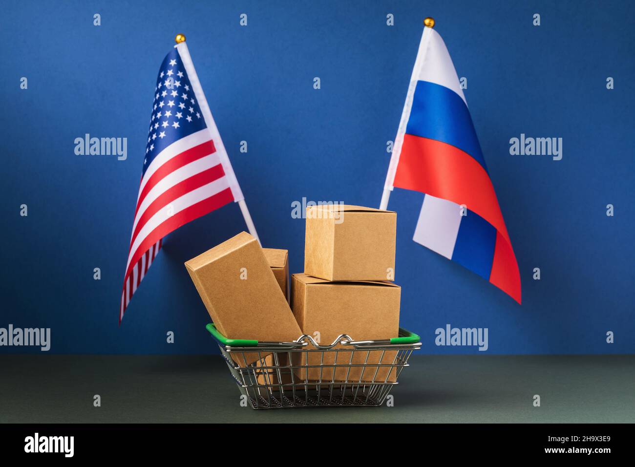Varie scatole in un cestino di cibo e due bandiere su uno sfondo blu, il concetto di commercio tra gli Stati Uniti e la Russia Foto Stock