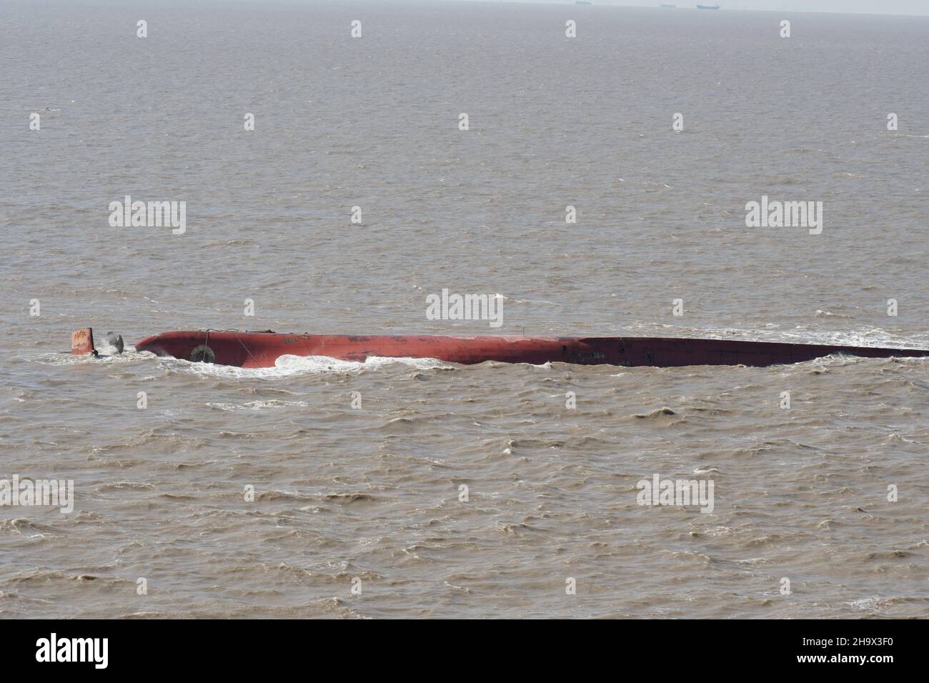 Fondo della nave capitolato dipinto di rosso marrone con timone visibile e elica in forte corrente. Foto Stock
