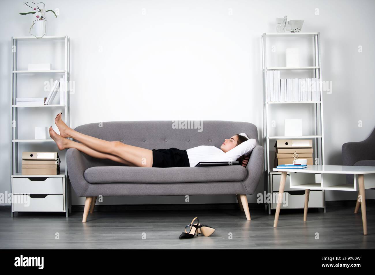 Giovane donna d'affari che dorme sul posto di lavoro in ufficio. Donna segretario dormire in abiti formali. Foto Stock