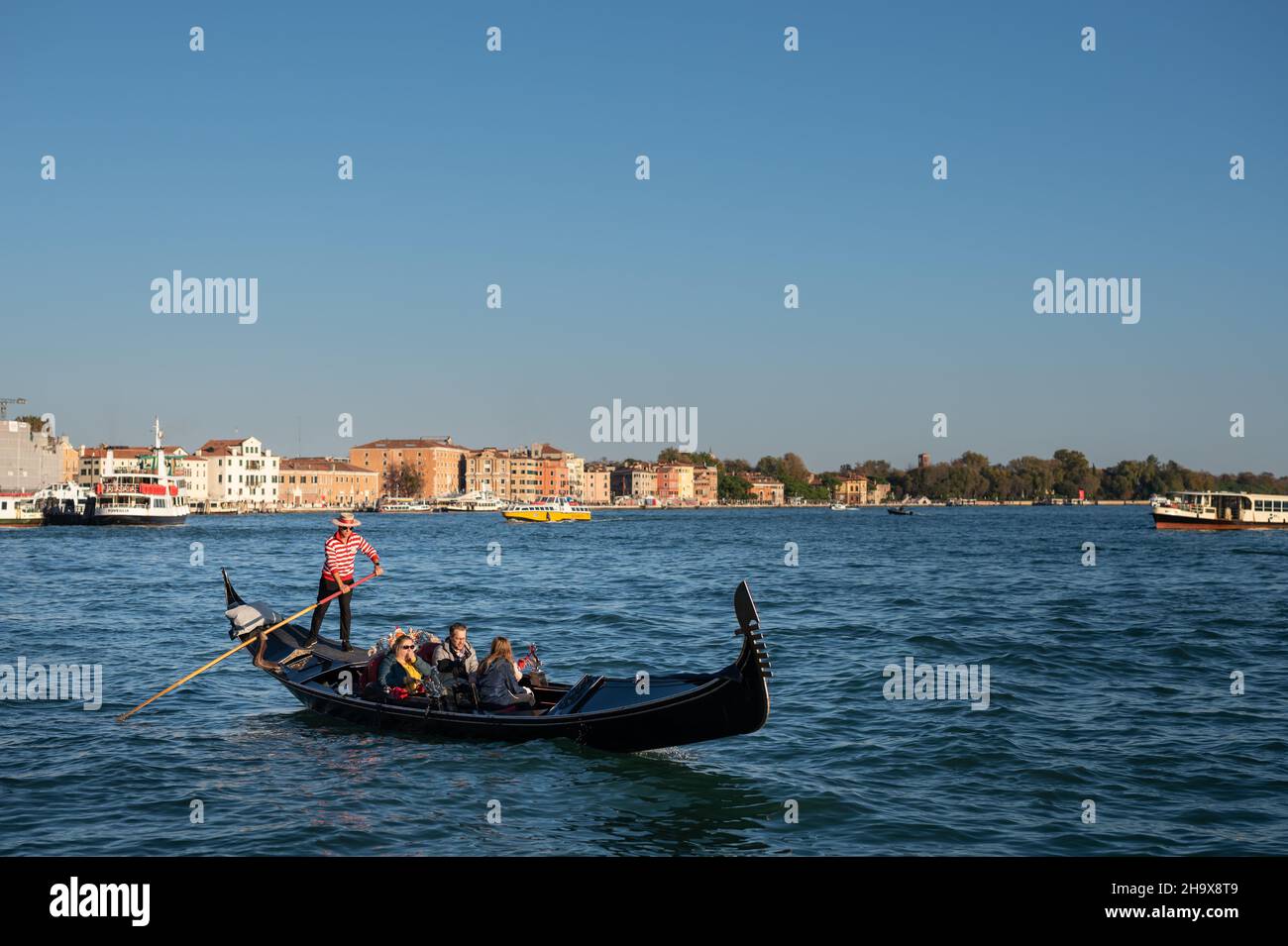 Venezia, Italia - 27 ottobre 2021: Gondola con turisti vicino a San Marco a Venezia in una giornata di sole in inverno, cielo blu Foto Stock