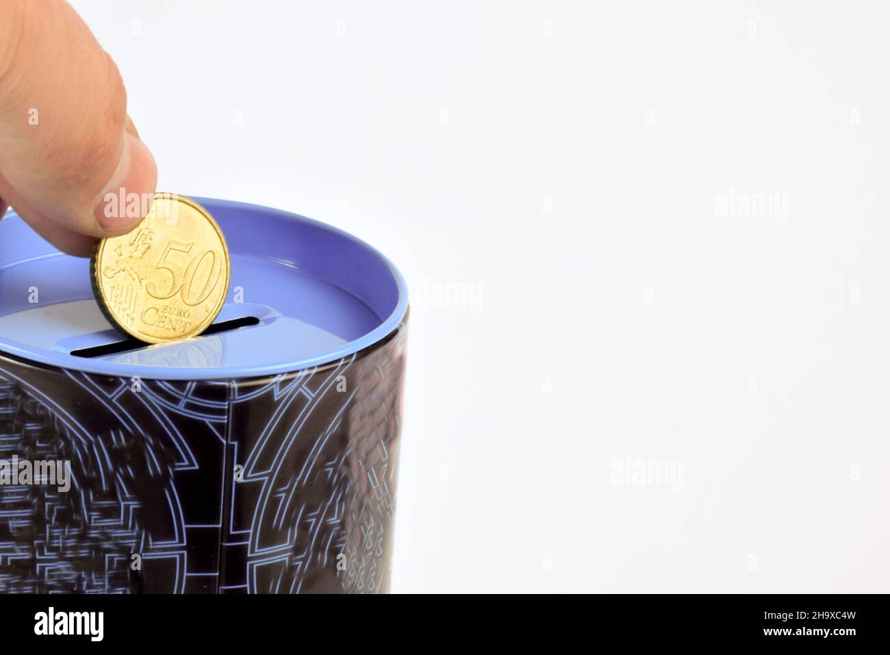 La mano tiene 50 centesimi di euro su una banca piggy su sfondo bianco di clipping. A destra c'è uno spazio vuoto per l'etichettatura o l'inserimento Foto Stock