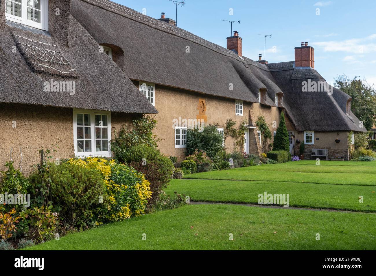 Una pittoresca fila di cottage con il tetto di paglia progettato da Sir Edwin Luytens nel villaggio di Ashby St partitari, Northamptonshire, Regno Unito Foto Stock