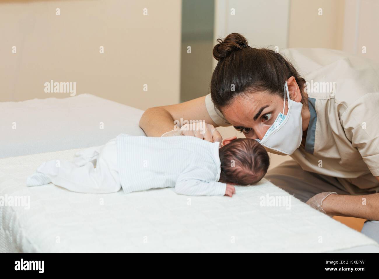 Fisioterapista femminile che esegue una stimolazione muscolare pro-decubito su un neonato. Foto Stock