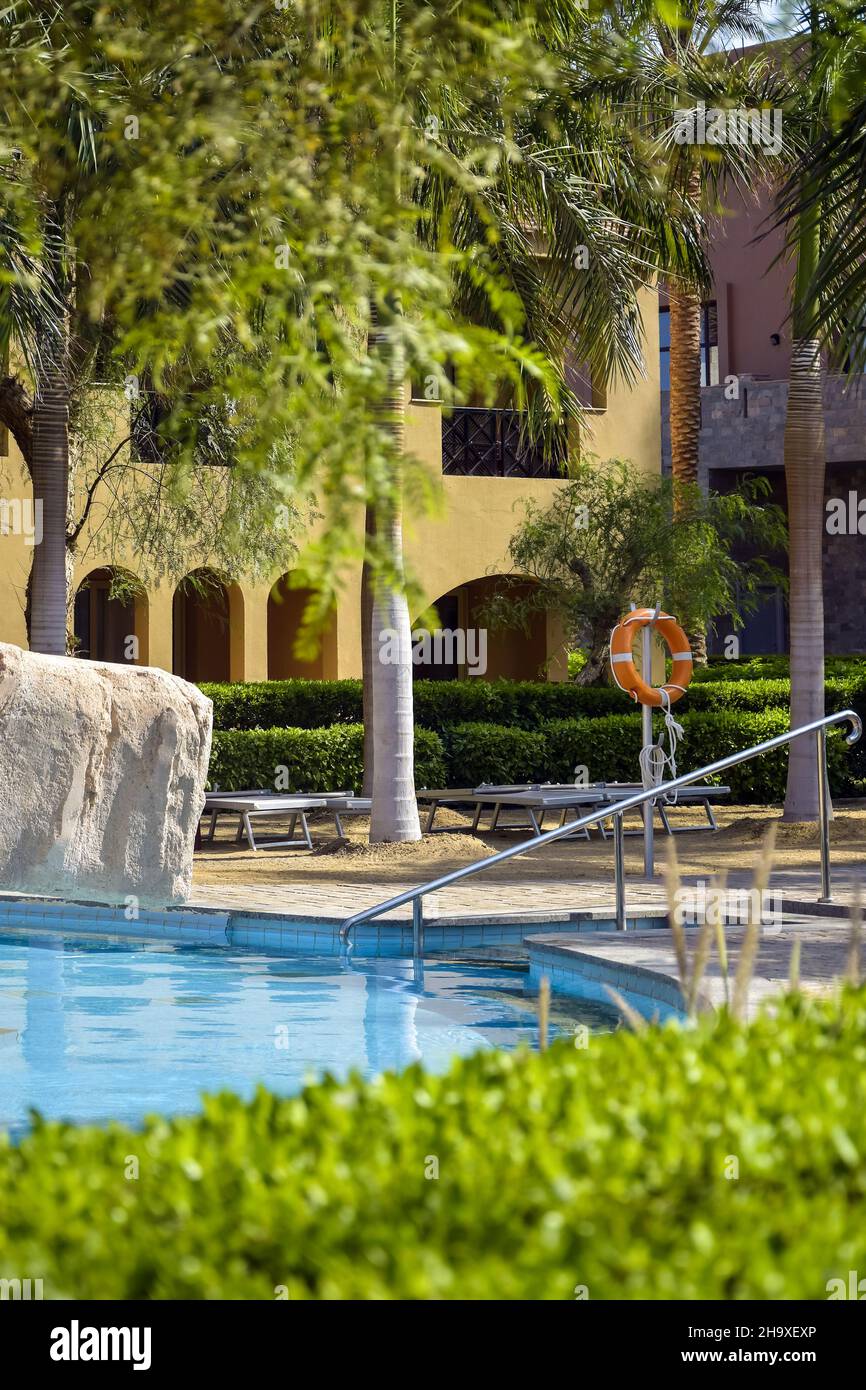 Piscina con acqua limpida e blu senza persone. Vacanza in resort. Il Lifebuoy e le sedie a sdraio si trovano vicino alla piscina. Hurghada, Egitto - Ottobre 202 Foto Stock