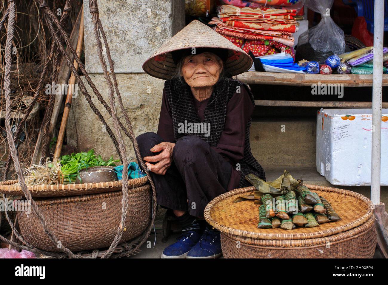 Ritratto di una vecchia donna che vende torta semplice al mercato del villaggio di Tho ha, Bac Giang, Vietnam Foto Stock