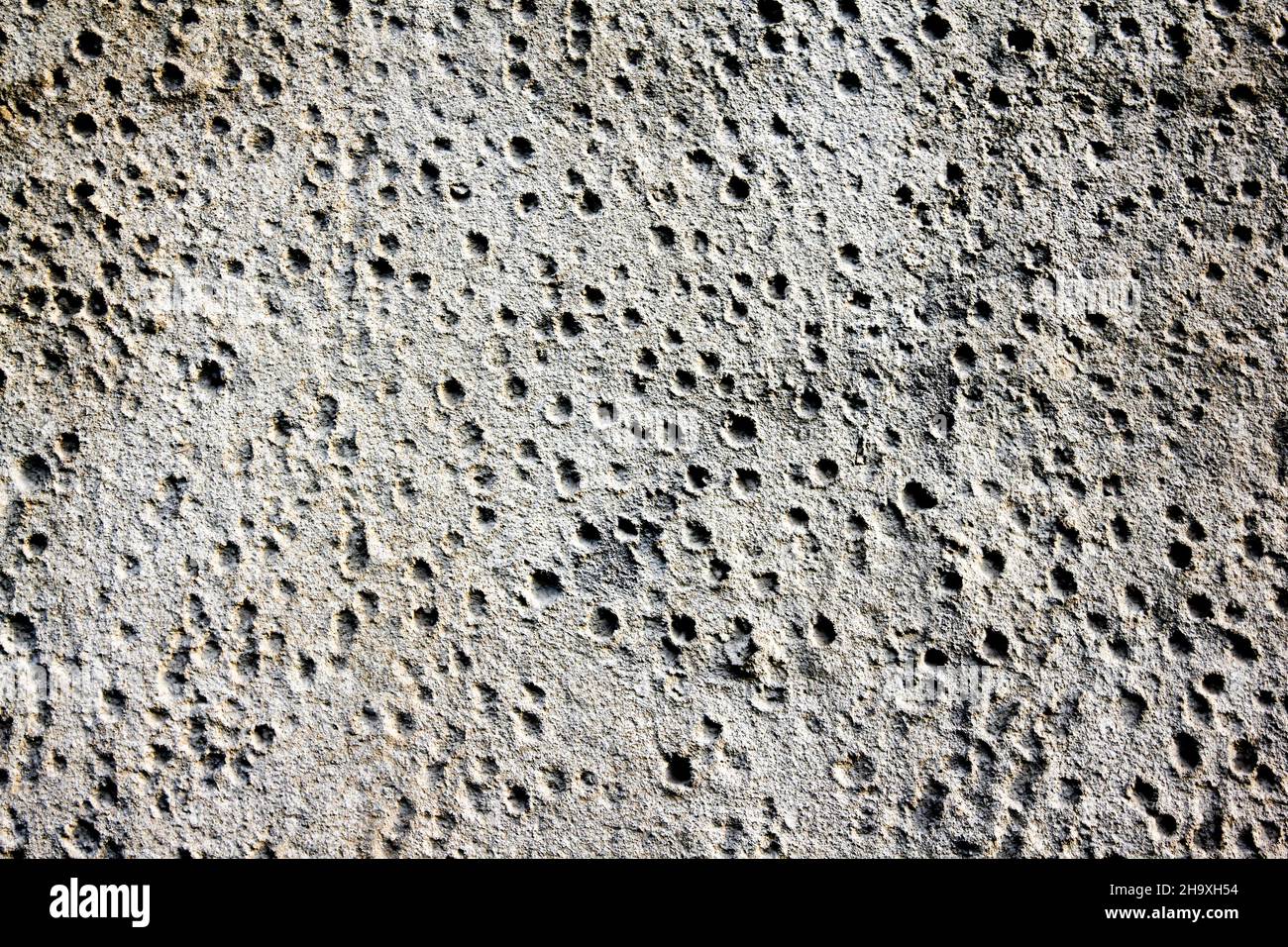 Parete in calcestruzzo con piccoli fori in bianco e nero. Foto Stock