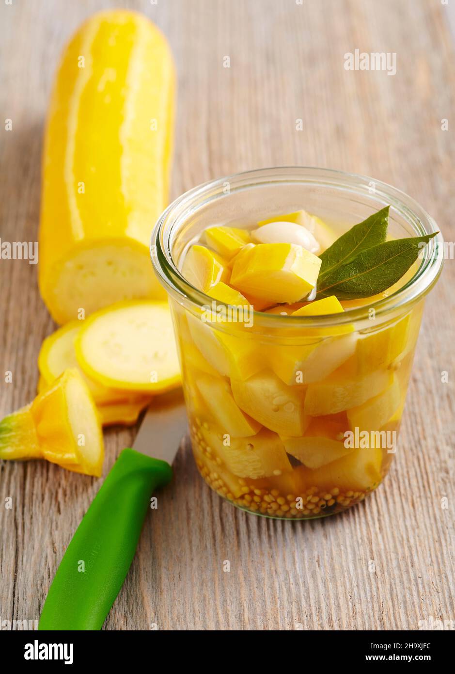 Zucchine gialle sottaceto con foglie di alloro, senape, aceto e zucchero in un vasetto Foto Stock