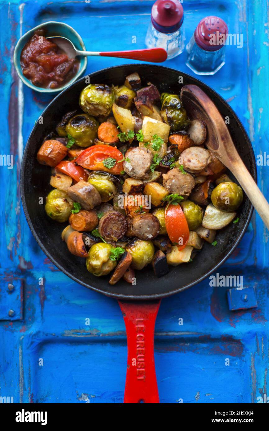 Salsicce con germogli di bruxelles, patate dolci e pomodori Foto Stock