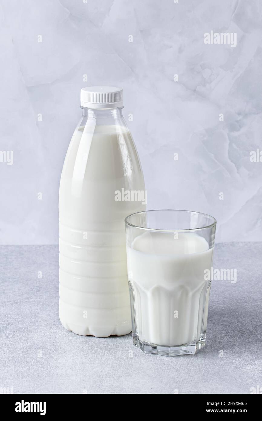 Bottiglia piena e bicchiere di latte su sfondo grigio del tavolo. Cibo sano, una fonte di calcio. Ingrediente di cottura, bevanda Foto Stock