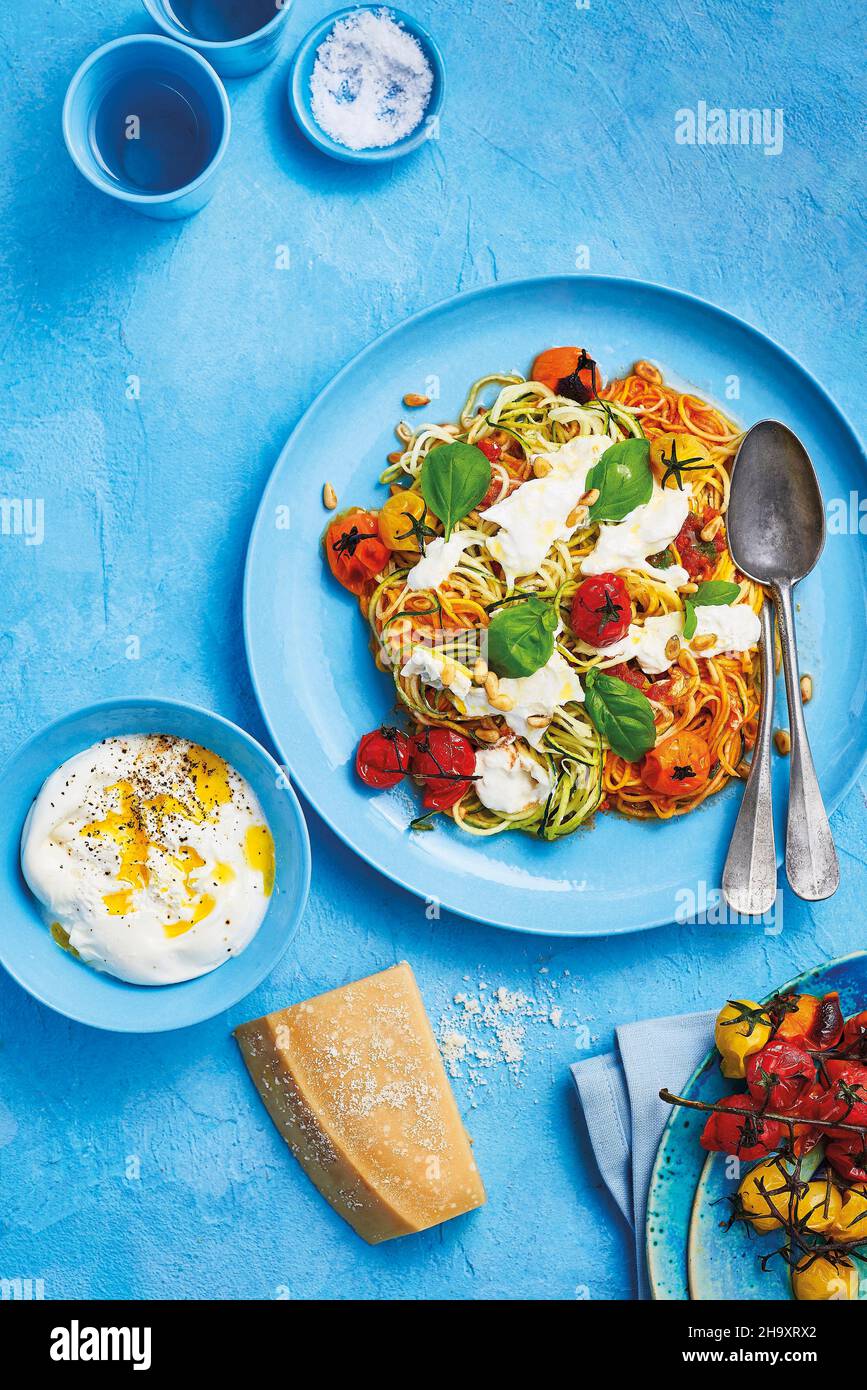 Courgetti arcobaleno con pomodori arrosto balsamici e buratta con pinoli e foglie di basilico Foto Stock