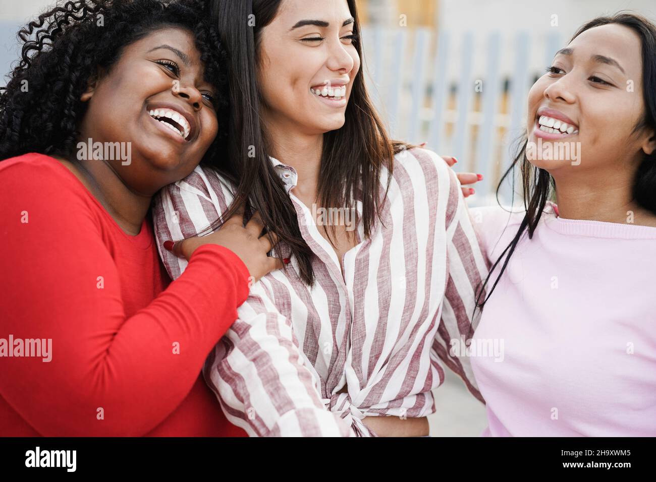 Le ragazze latine felici godono il tempo insieme all'aperto intorno alla città - fuoco sul fronte africano della ragazza Foto Stock