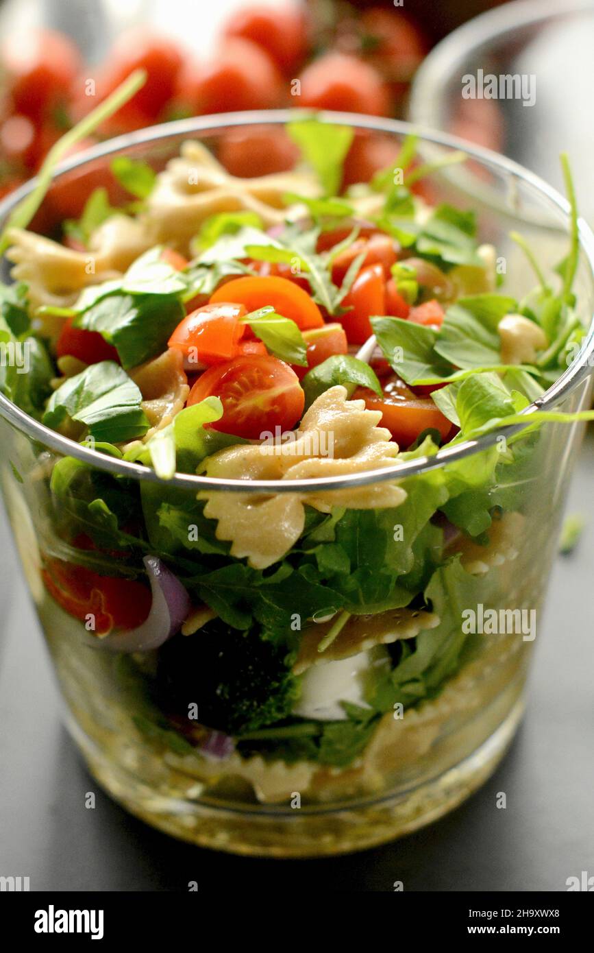 Insalata di pasta con pomodori e basilico in un bicchiere Foto Stock