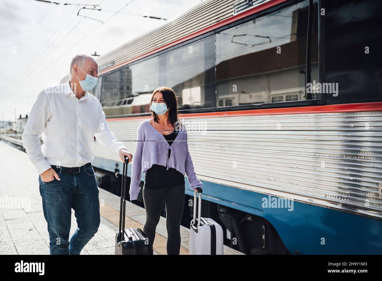 Turisti con valigie e maschere sulla piattaforma accanto al treno, Portogallo Foto Stock