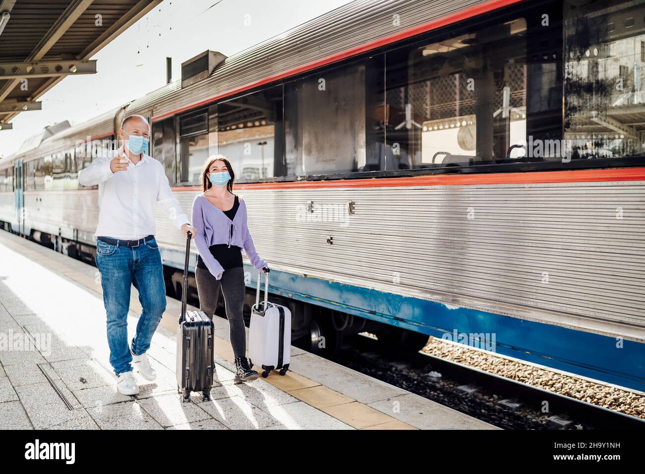 Turisti con valigie e maschere sulla piattaforma accanto al treno, Portogallo Foto Stock