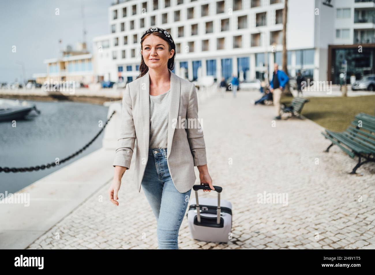 Giovane donna con valigia a piedi in ambienti urbani, Faro, Portogallo Foto Stock