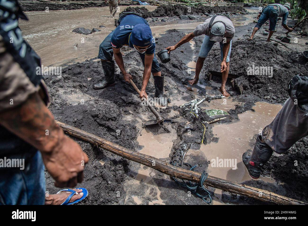 Kamar Kajang, Indonesia. 09th Dic 2021. Gli abitanti del villaggio cercano di rimuovere una moto che è stata sepolta dalla lava fredda dopo l'eruzione del monte Semeru a Kamar Kajang, Lumajang. Almeno 14 persone sono morte e decine di feriti dopo che il Monte Semeru, un vulcano nella provincia di Giava orientale dell'Indonesia, eruttò il sabato, lanciando torri di cenere e nuvole calde che coprirono villaggi vicini. Credit: SOPA Images Limited/Alamy Live News Foto Stock