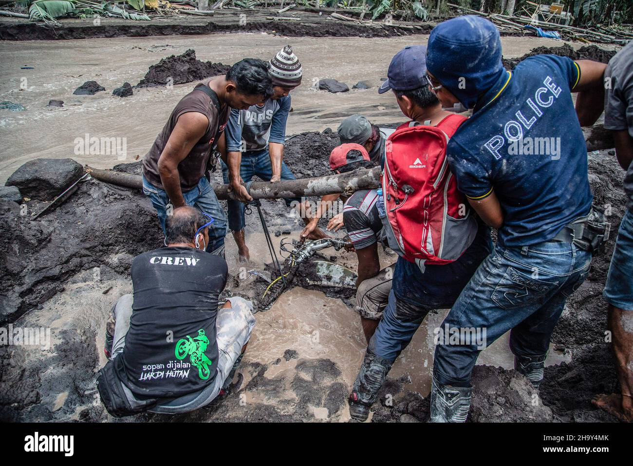 Kamar Kajang, Indonesia. 09th Dic 2021. Gli abitanti del villaggio cercano di rimuovere una moto che è stata sepolta dalla lava fredda dopo l'eruzione del monte Semeru a Kamar Kajang, Lumajang. Almeno 14 persone sono morte e decine di feriti dopo che il Monte Semeru, un vulcano nella provincia di Giava orientale dell'Indonesia, eruttò il sabato, lanciando torri di cenere e nuvole calde che coprirono villaggi vicini. Credit: SOPA Images Limited/Alamy Live News Foto Stock