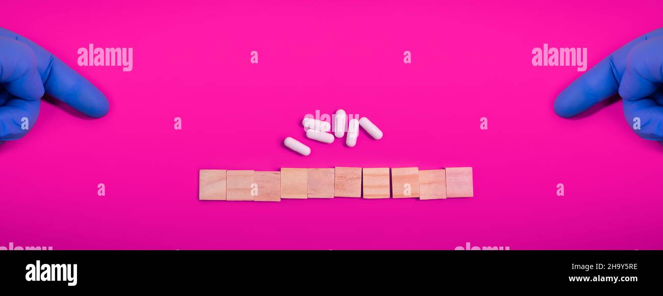Le mani nei guanti medici puntano su blocchi di legno su sfondo viola colorato con pillole di medicina. Concept book coprire medico scientifico o biologico t Foto Stock