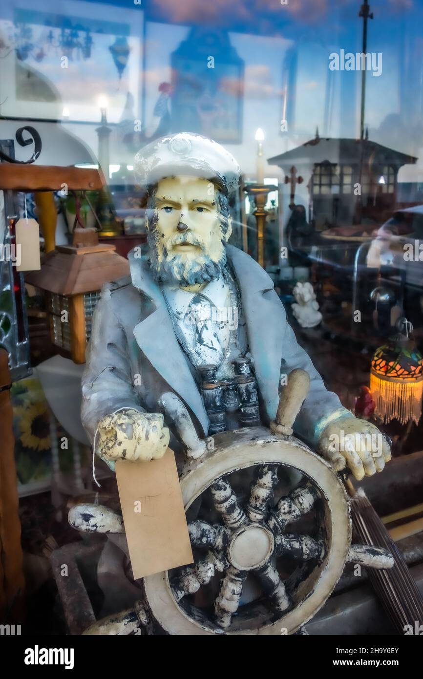 Vintage personaggio marinaio in legno con una ruota di navi e binocoli, preso attraverso una finestra di un negozio di antiquariato sul lungomare di Hastings, 31st luglio 2021 Foto Stock