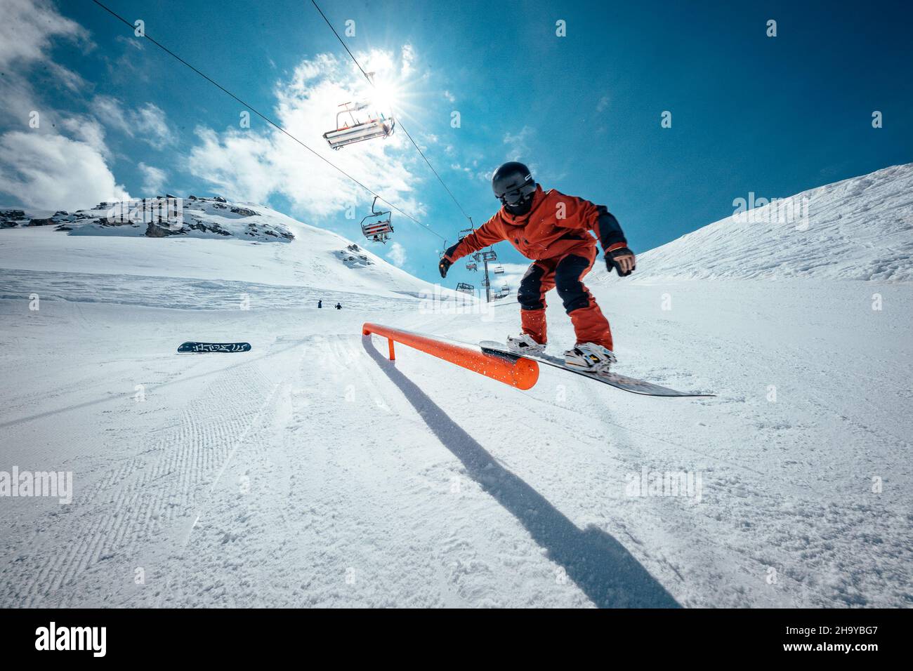 Un giro di 50/50 snowboarder su una ferrovia nello Snowpark di Corvatsch, Svizzera. Foto Stock