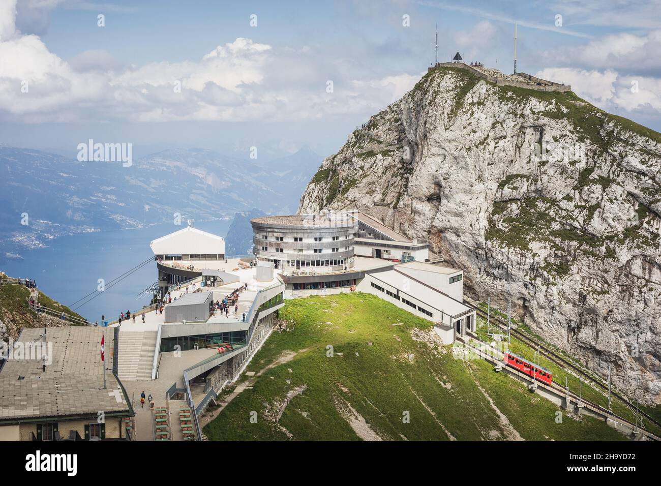 Vista soleggiata sulla cima del Monte Pilatus, con vista sul lago di Lucerna, con un treno a cremagliera che arriva in Svizzera Foto Stock